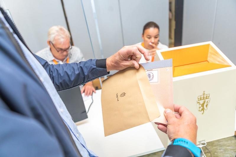 Person putter stemmeseddel i konvolutt - Klikk for stort bilete