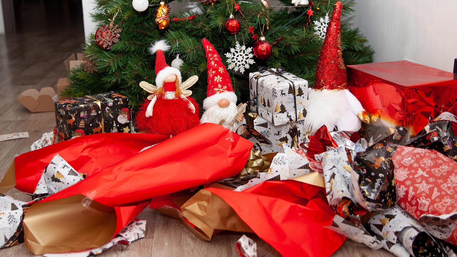Julegavepapri-søppel foran et juletre og julenisse-figurer