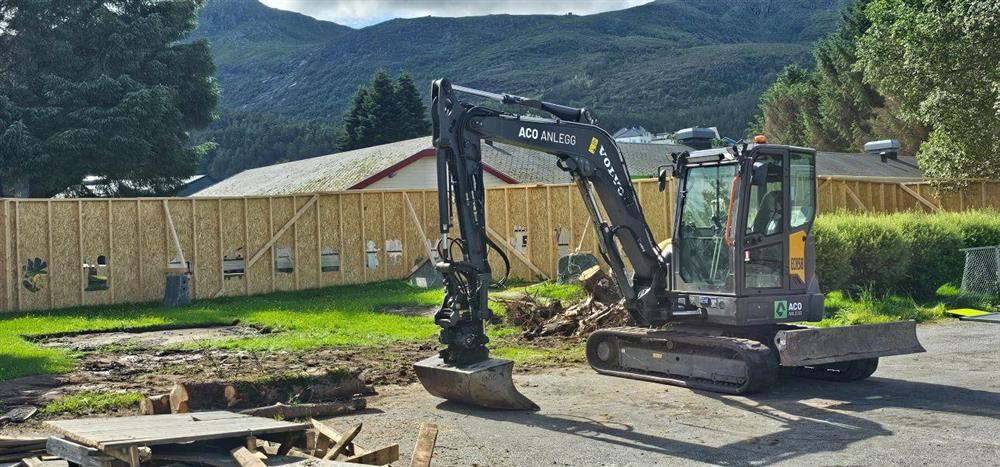 byggjerde i tre og gravemaskin - Klikk for stort bilete