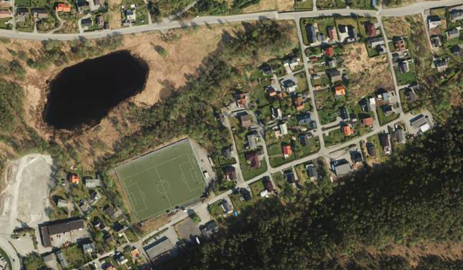 flyfoto over område med bustader og idrettsanlegg - Klikk for stort bilete