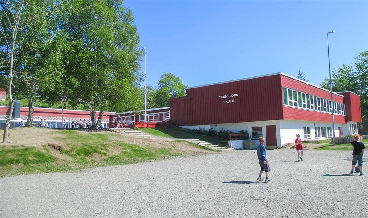 Foto av Tennfjord skule frå utsida med born som leiker - Klikk for stort bilete